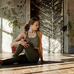 A woman does a yoga pose on a mat in a bright, minimalist studio.