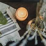A serene spa setup featuring a jade roller, gua sha, towel, and candle for ultimate relaxation.