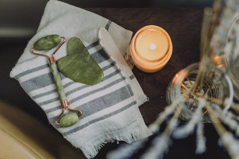 A serene spa setup featuring a jade roller, gua sha, towel, and candle for ultimate relaxation.