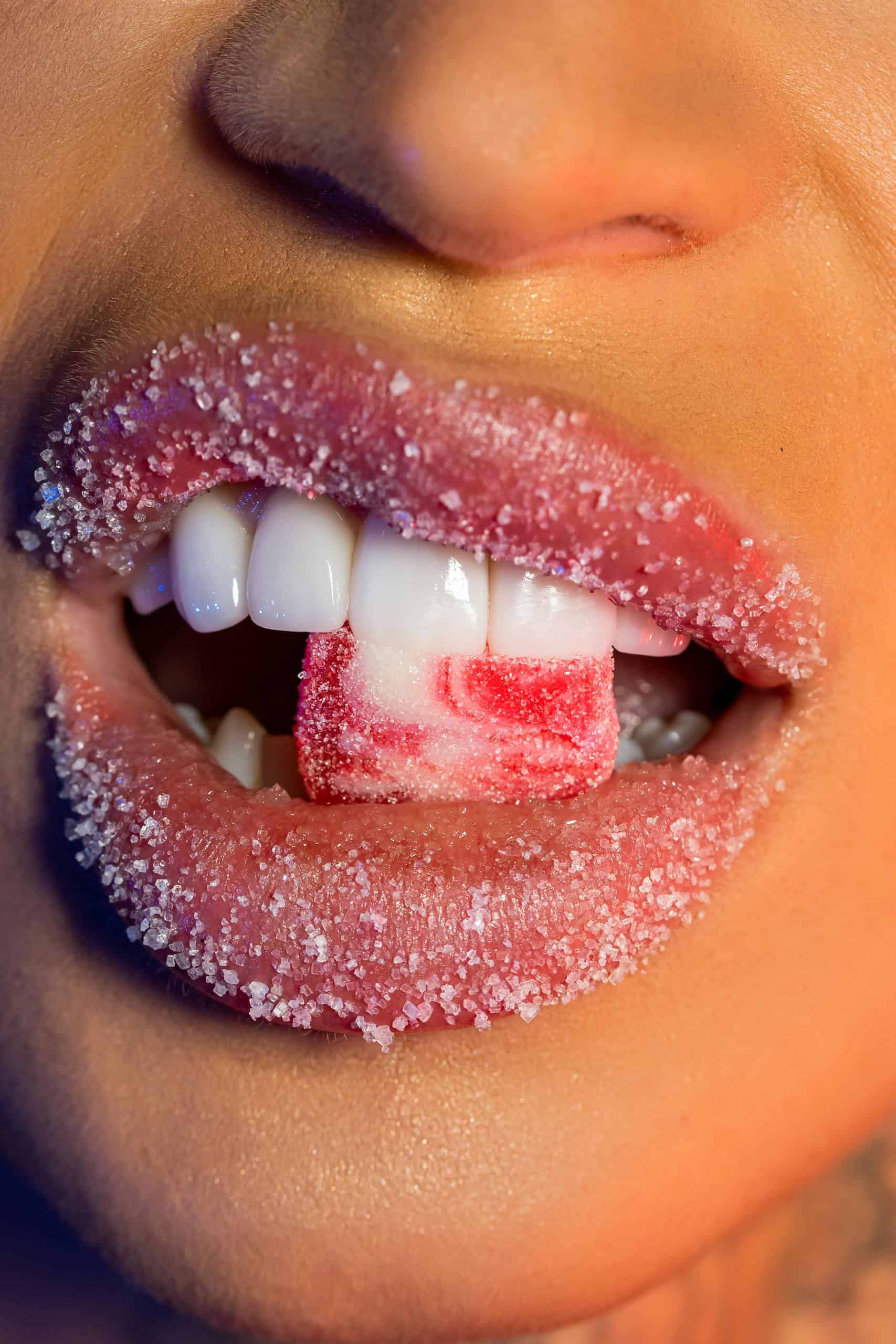 Vibrant close-up of sugar-covered lips biting candy, highlighting texture.